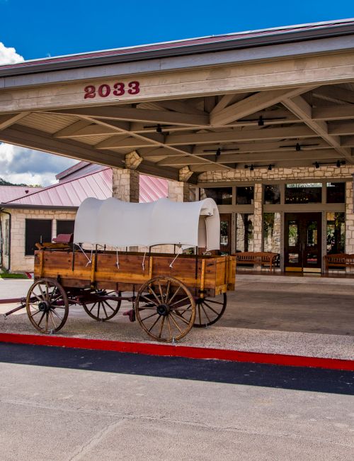 The image shows a covered entryway with a vintage wooden wagon on display, beneath a roof with the number 20332.