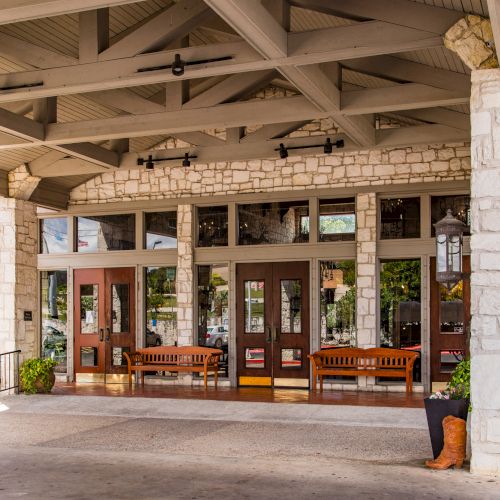 The image shows a building entrance with wooden benches, stone walls, and decorative elements, including a boot sculpture on the right.