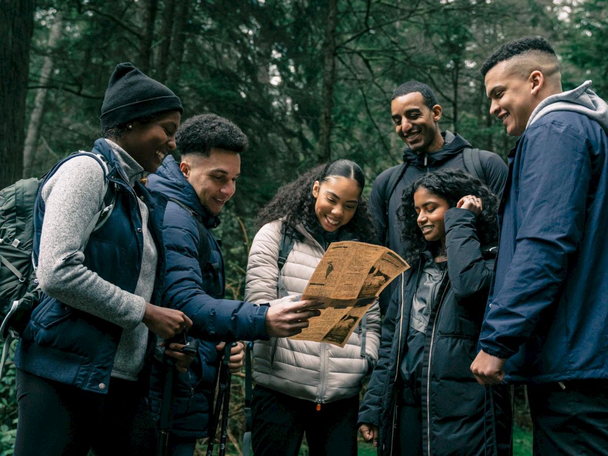 A diverse group of friends in a forest, looking at a map together, planning a hike or adventure as they smile and collaborate.